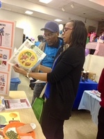 Gallery Photo of Explaining the plate method to a health fair attendee at a health and wellness fair,